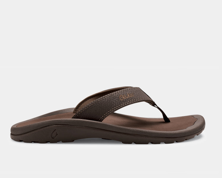 A pair of brown Ohana sandals by Olukai, featuring a water-resistant synthetic strap and a non-marking rubber outsole with a coral reef lug design.