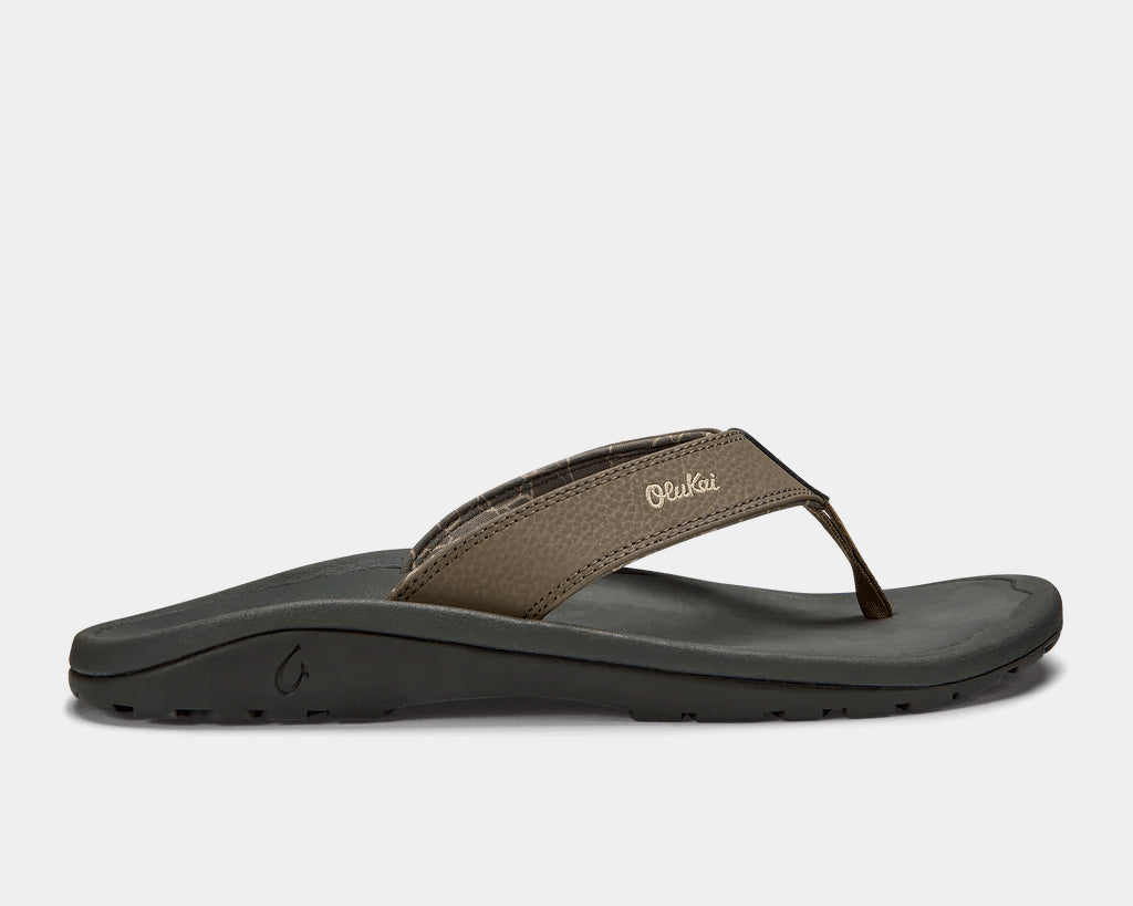 A pair of brown Ohana sandals by Olukai, featuring a water-resistant synthetic strap and a non-marking rubber outsole with a coral reef lug design.