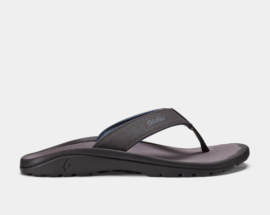 A pair of grey Ohana sandals by Olukai, featuring a water-resistant synthetic strap and a non-marking rubber outsole with a coral reef lug design.