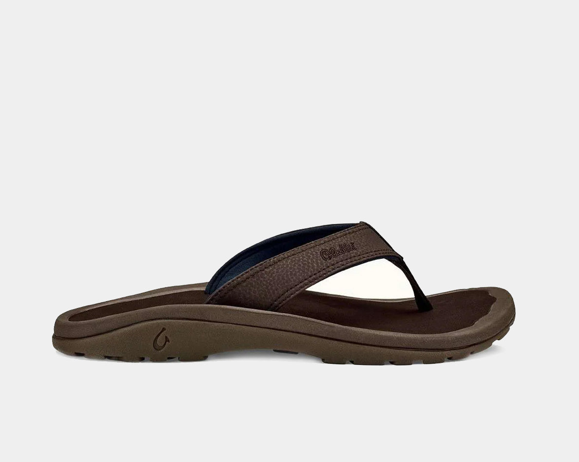 A pair of brown Ohana sandals by Olukai, featuring a water-resistant synthetic strap and a non-marking rubber outsole with a coral reef lug design.