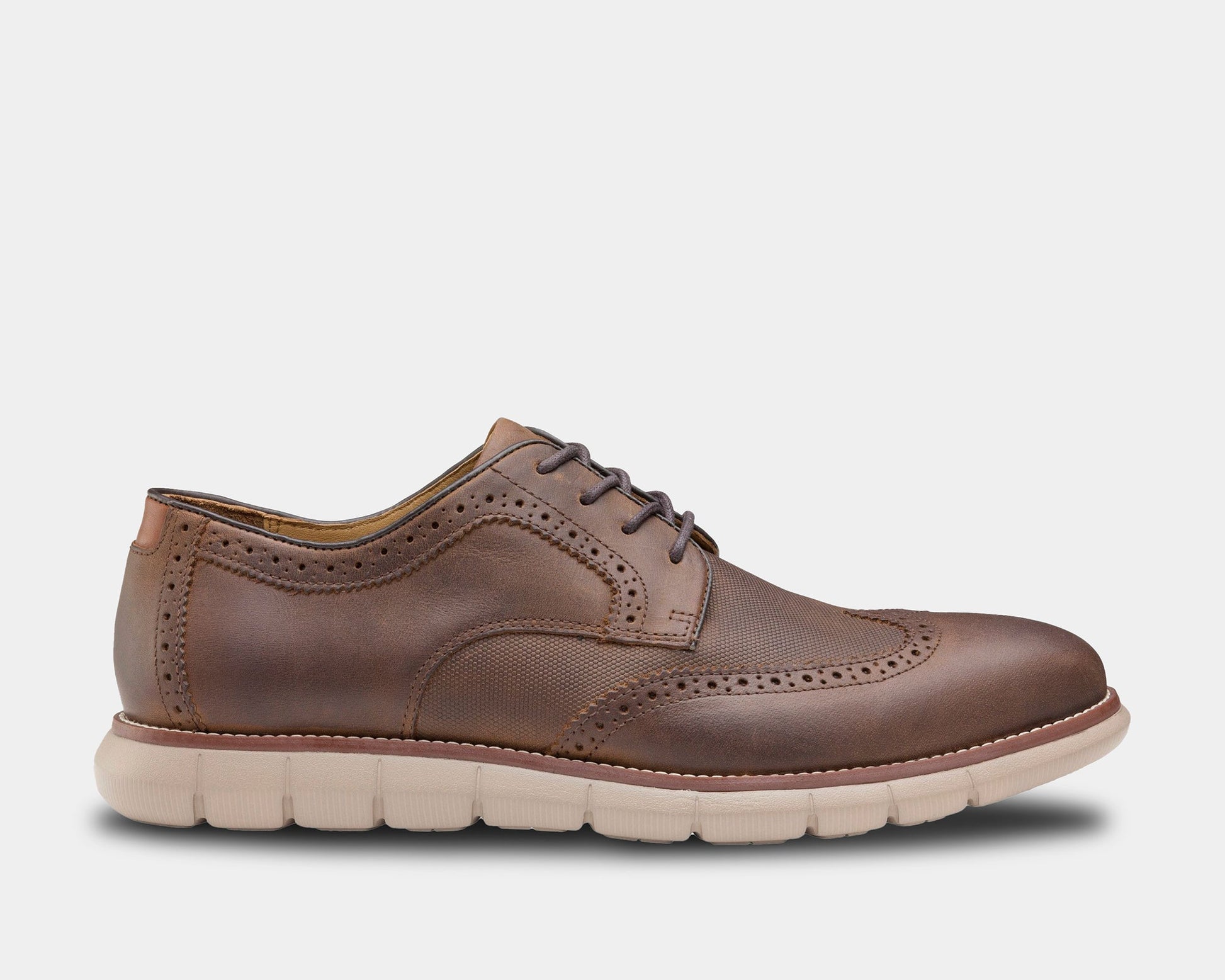 A brown, leather wingtip Oxford shoe with a rubber sole, featuring lace-up closure and a side stretch gore.